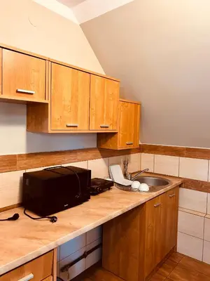 a kitchen with wooden cabinets and a sink at Noclegi Missterium in Wojnicz