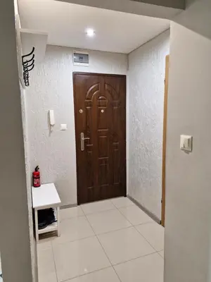 a hallway with a brown door and a white tile floor at Na Podwalu in Jaworzno
