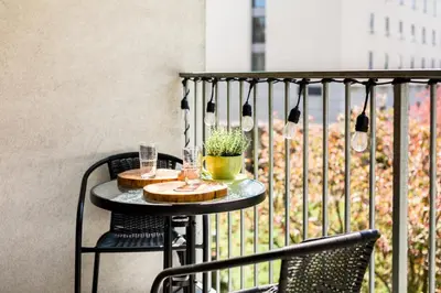 a table with two glasses and a plant on a balcony at RentPlanet - Angel Plaza in Kraków