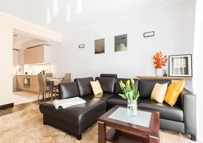 a living room with a black leather couch and a table at RentPlanet - Angel Plaza in Kraków
