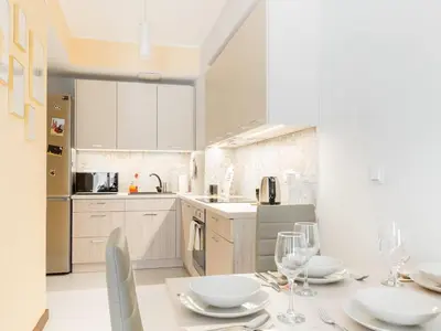 a kitchen with white cabinets and a table with wine glasses at RentPlanet - Angel Plaza in Kraków