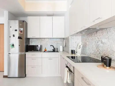 a kitchen with white cabinets and a stainless steel refrigerator at RentPlanet - Angel Plaza in Kraków