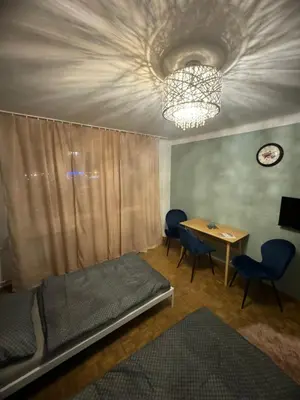 a bedroom with a bed and a table and a chandelier at Mieszkaj u Marty stale na Stałym in Jaworzno