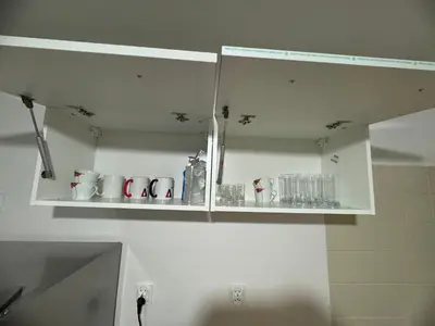a white kitchen cabinet with cups and dishes on it at Mieszkaj u Marty stale na Stałym in Jaworzno