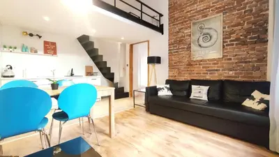 a living room with a black couch and a brick wall at Krowoderska 55 by Homeprime in Kraków