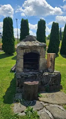 a stone oven in a grassy field with trees at Mały domek in Lubomierz