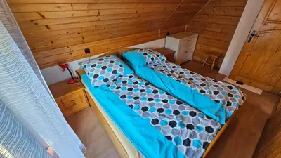 a large bed in a room with wooden walls at Mały domek in Lubomierz