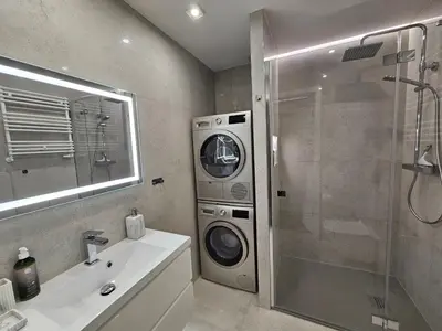 a bathroom with a washing machine next to a shower at Bagry Luxury Apartment 19 in Kraków