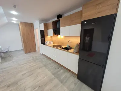 a kitchen with a black refrigerator and wooden floors at Apart Bogi in Szczyglice