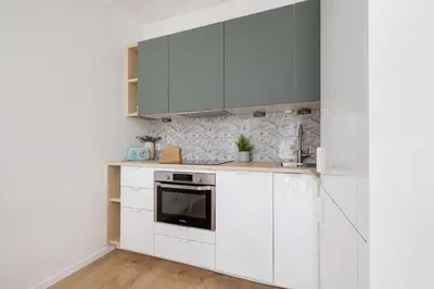 a kitchen with white cabinets and a stove at Modern Apartment with Parking near Tauron Arena Kraków by Noclegi Renters in Kraków