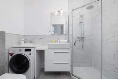 a white bathroom with a washing machine and a shower at Modern Apartment with Parking near Tauron Arena Kraków by Noclegi Renters in Kraków