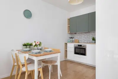 a white kitchen with a table and chairs at Modern Apartment with Parking near Tauron Arena Kraków by Noclegi Renters in Kraków