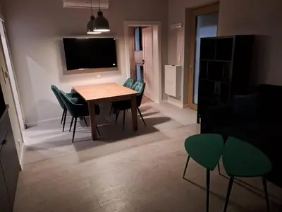 a living room with a wooden table and green chairs at Leśna24 in Rabka-Zdroj