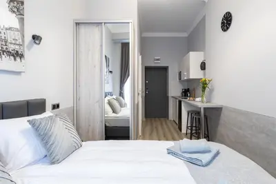 a bedroom with a white bed and a kitchen at DOLCE VITA Elegant Apartments in Kraków