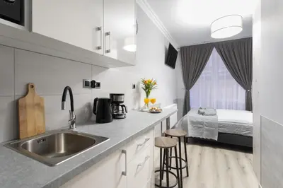 a kitchen with a sink and a bed in a bedroom at DOLCE VITA Elegant Apartments in Kraków