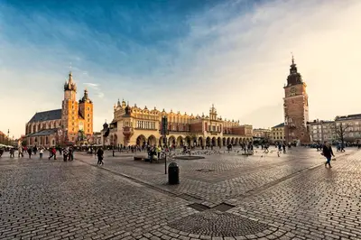 a group of people walking around a city with a clock tower at Apartament z jacuzzi Kraków Rynek in Kraków
