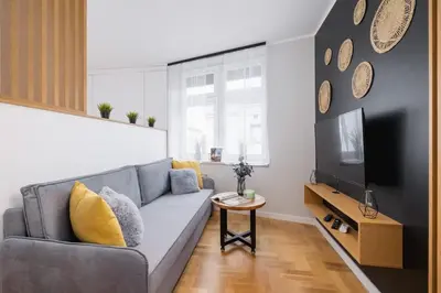a living room with a gray couch and a tv at Apartamenty Warszauera z Klimatyzacją na Krakowskim Kazimierzu by Noclegi Renters in Kraków