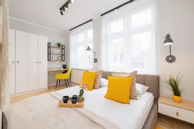 a bedroom with a bed with yellow pillows at Apartamenty Warszauera z Klimatyzacją na Krakowskim Kazimierzu by Noclegi Renters in Kraków