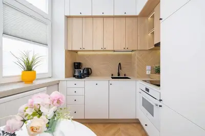 a kitchen with white cabinets and pink flowers in a vase at Apartamenty Warszauera z Klimatyzacją na Krakowskim Kazimierzu by Noclegi Renters in Kraków