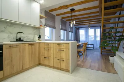 a kitchen with wooden cabinets and a dining room at Apartament Mikołaja w Rabce in Rabka