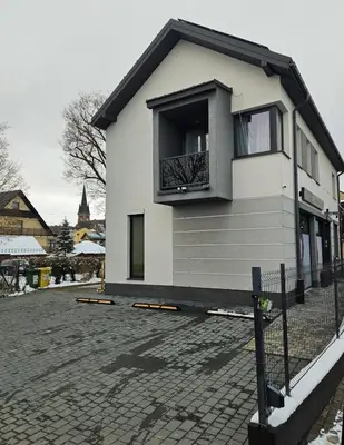 a white house with a balcony on a brick street at Apartament Mikołaja w Rabce in Rabka
