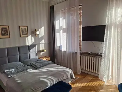 a bedroom with a bed and a large window at Apartament studio z widokiem na Rynek in Bochnia