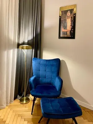 a blue chair and a stool in a room at Apartament studio z widokiem na Rynek in Bochnia