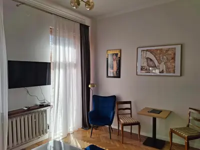 a living room with a blue chair and a table at Apartament studio z widokiem na Rynek in Bochnia
