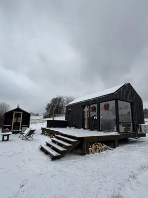 a black building with a picnic table in the snow at Domek na Odludziu - Tiny House in Spytkowice