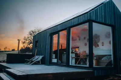 a green building with a deck with a chair on it at Domek na Odludziu - Tiny House in Spytkowice