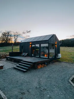 a small black house with a porch and stairs at Domek na Odludziu - Tiny House in Spytkowice