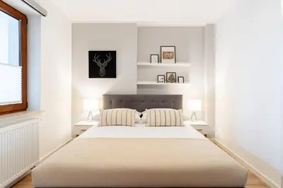 a white bedroom with a large bed with two lamps at Native Apartments Barska 13 in Kraków