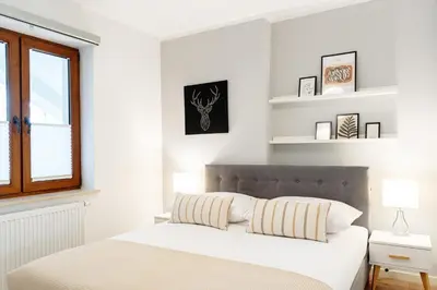 a bedroom with a bed with white walls and a window at Native Apartments Barska 13 in Kraków