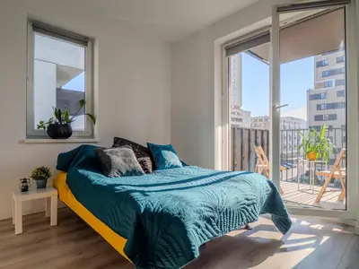 a bedroom with a bed and a large window at Miły Pobyt w mieście in Kraków