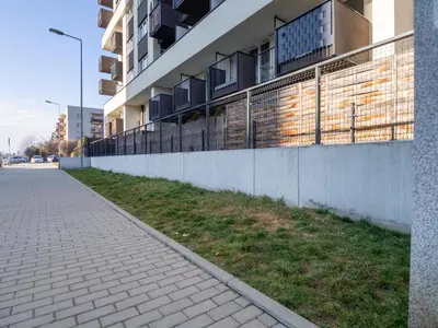 a sidewalk next to a building with a fence at Miły Pobyt w mieście in Kraków