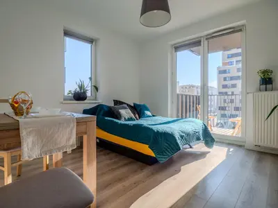 a bedroom with a bed and a table and windows at Miły Pobyt w mieście in Kraków