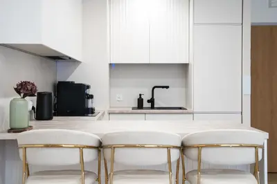 a kitchen with white cabinets and gold bar stools at Luxury Apartments in Kraków