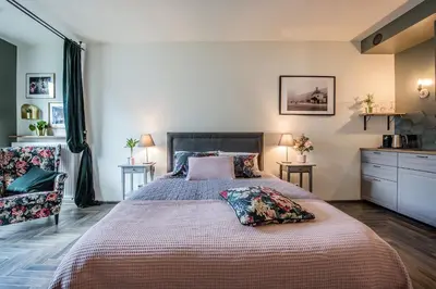 a bedroom with a large bed and a chair at Rajska Old Town Suites in Kraków