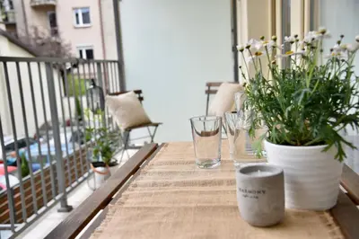 a wooden table with glasses and flowers on a balcony at Kraków Apartments - Friedleina Studio Apartments in Kraków