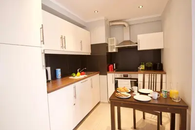 a kitchen with white cabinets and a wooden table at Kraków Apartments - Friedleina Studio Apartments in Kraków