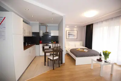 a bedroom with a bed and a table and a kitchen at Kraków Apartments - Friedleina Studio Apartments in Kraków