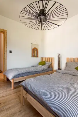 two beds in a room with a large chandelier at Stodołówka in Budzów