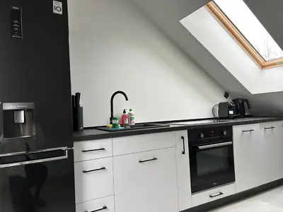 a kitchen with white cabinets and a black appliance at Villa Kraków in Kraków