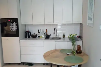 a kitchen with white cabinets and a wooden table at Modern apartament in the Old Town in Kraków