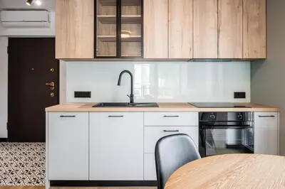 a kitchen with white cabinets and a sink and a table at Dodo Acomodo 7 in Kraków