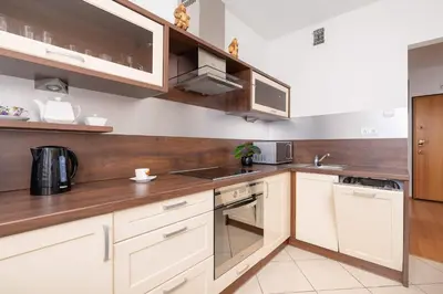 a kitchen with white cabinets and wooden counters at Bright Apartment near ICE Kraków with Air Conditioning and Parking by Noclegi Renters in Kraków