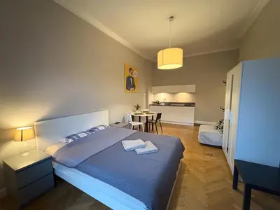 a bedroom with a large bed and a kitchen at Central Place Warszawska in Kraków