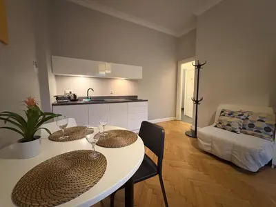 a living room with a table and chairs and a kitchen at Central Place Warszawska in Kraków