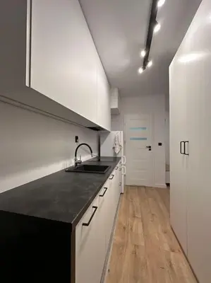 a kitchen with white cabinets and a black counter top at Nowoczesny apartament z ogrodem in Kraków