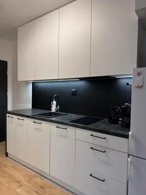 a kitchen with white cabinets and a black counter top at Nowoczesny apartament z ogrodem in Kraków